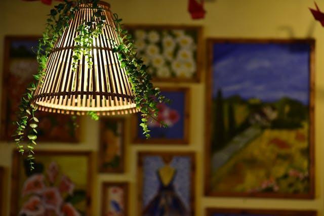 Decorative pendant light with hanging greenery and colorful framed artwork on the wall in a cozy guest house interior